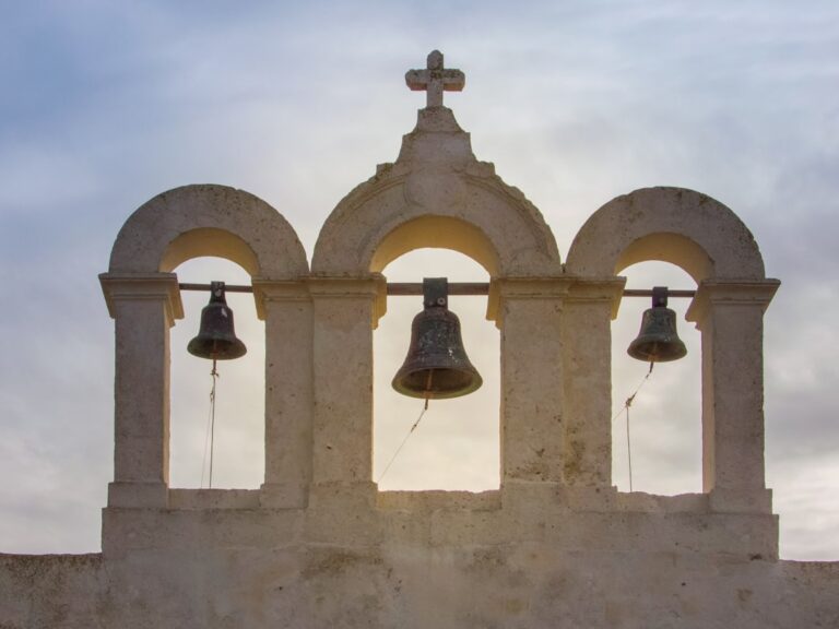 Three bells framed by arches, above a church on the island of Comino, Malta.